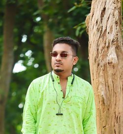 Portrait of young man standing against trees