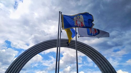 Low angle view of flags against cloudy sky