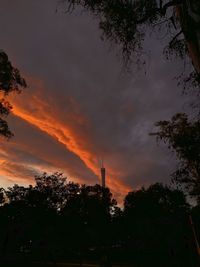 Low angle view of silhouette trees and buildings against sky at sunset