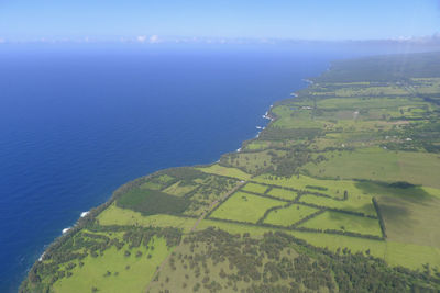 Scenic view of agricultural field by sea against sky