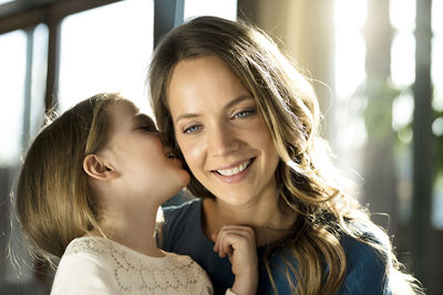 Smiling girl whispering into her mother's ear