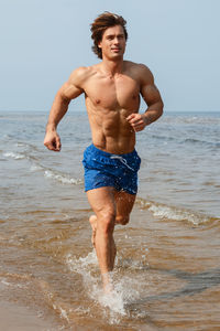 Shirtless man splashing water at beach