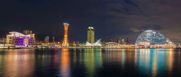 Illuminated city by river at night