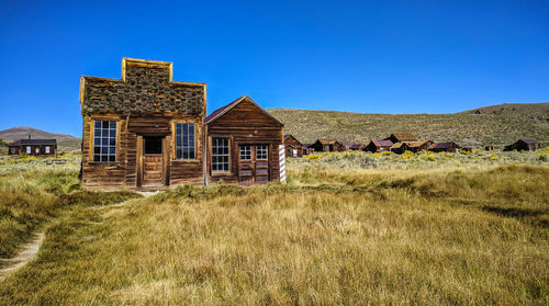 House on field against clear blue sky