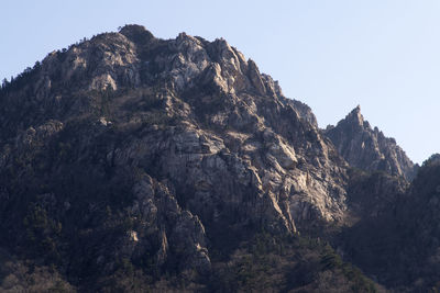 Low angle view of rocky mountains against clear sky