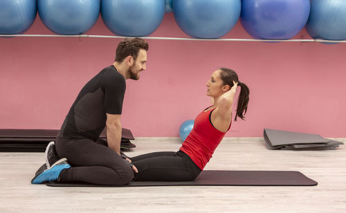 Side view of man training woman in gym