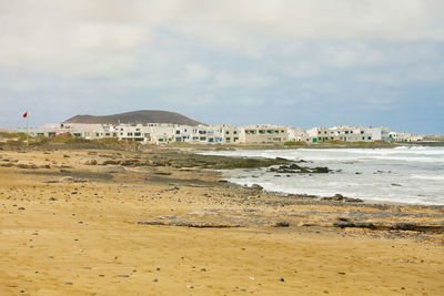 Scenic view of beach by buildings against sky