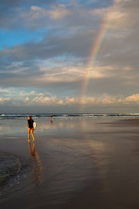 Man standing on beach against sky during sunset