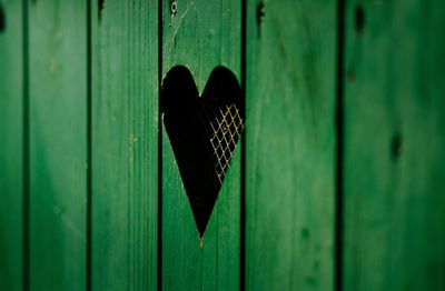 Heart shape window on green wooden door