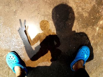 Low section of woman showing peace sign on puddle