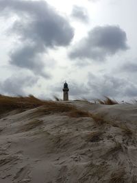 Lighthouse on street amidst buildings against sky