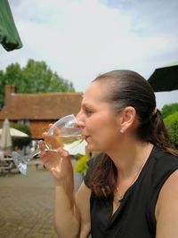 Woman drinking wine in city against sky