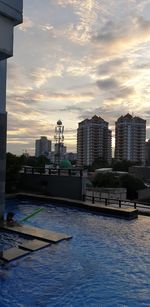 City by river against sky during sunset