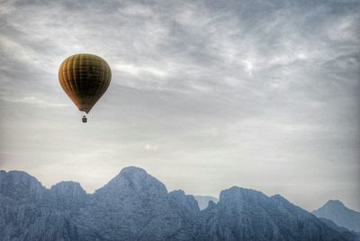 Hot air balloon flying over mountains against sky