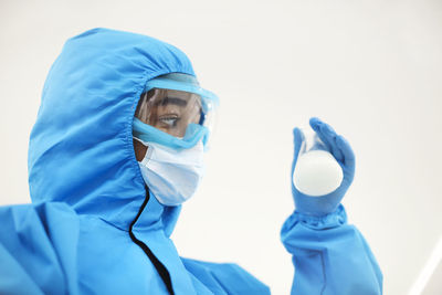 Portrait of doctor wearing protective mask against clear sky