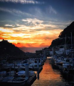 Boats moored at harbor against sky during sunset