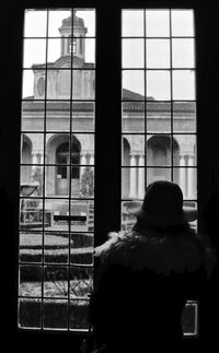 Rear view of a woman looking through window