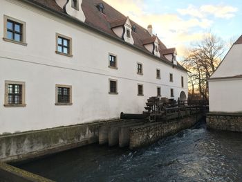 Buildings by river against sky in city