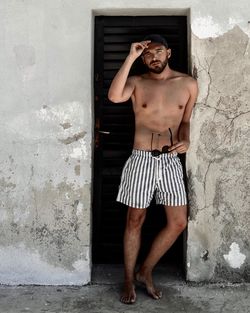 Portrait of young man standing against wall