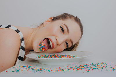 Close-up of woman with confetti against gray background