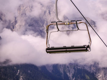 Ski lift in mid air against cloudy mountain