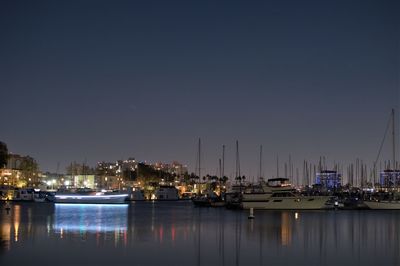 Sailboats moored in harbor at night