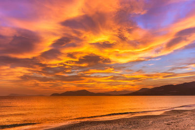 Scenic view of sea against dramatic sky during sunset