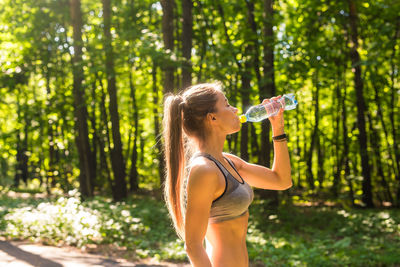 Full length of woman drinking water from bottle