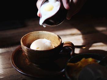 Cropped hand of person pouring liquid in sweet food on table