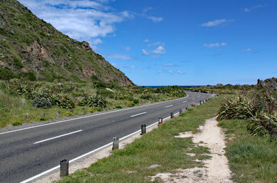 Road leading towards mountains against sky