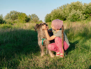 Little girl hugging playing with dog walking spending time together. child with pet in summer meadow