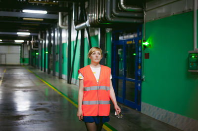 Young woman wearing reflective clothing while walking in factory