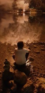 Rear view of boy sitting on rock