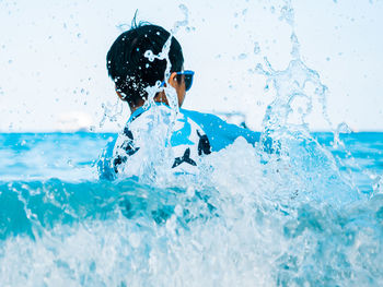 Rear view of boy splashing water in sea