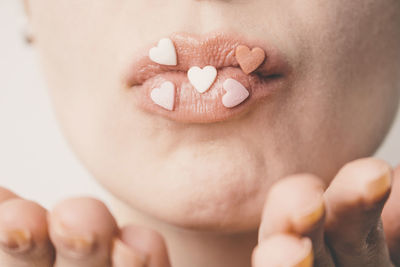 Close-up of heart shape candies on woman lips