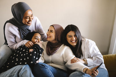 Cheerful women sitting together on sofa at home