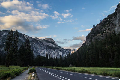 Empty road by mountains against sky