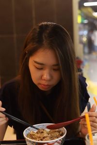 Young woman eating food on table in restaurant