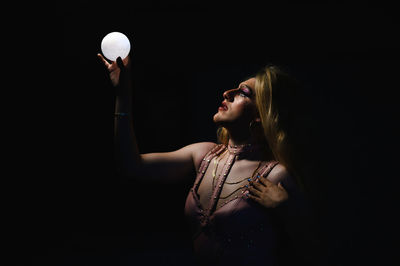 Portrait of woman standing against black background