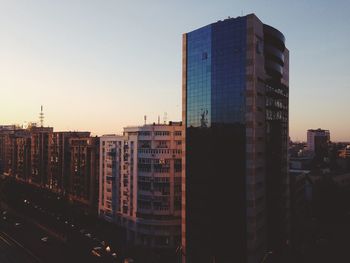 Modern cityscape against sky during sunset