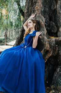 Young woman wearing mask on tree trunk