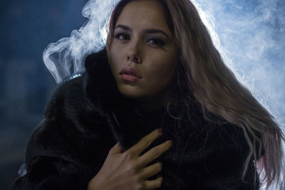 Close-up portrait of young woman standing against sky at night