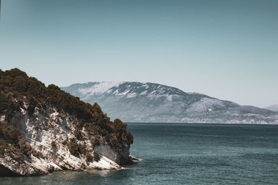 Scenic view of sea and mountains against clear sky