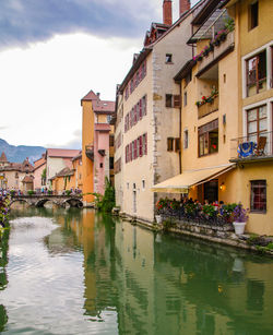 Houses by river in city against sky