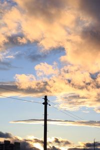 Low angle view of electricity pylon against cloudy sky