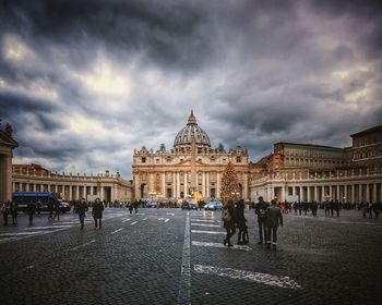 People at town square against cloudy sky