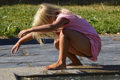 Side view of girl crouching on footpath