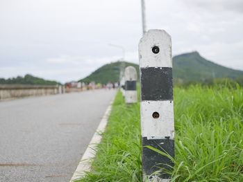 Information sign on field by road against sky