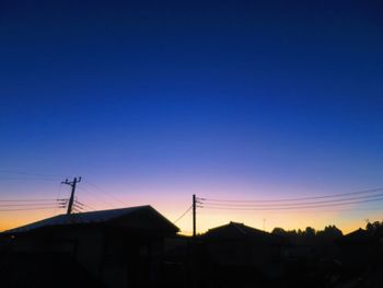 Silhouette houses against sky during sunset