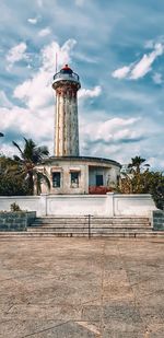 Lighthouse by building against sky